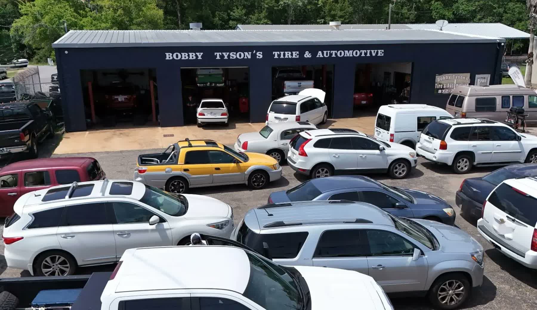 Aerial view of Bobby Tyson's Tire & Automotive: the navy shop building with four open bays and a lot full of customer vehicles